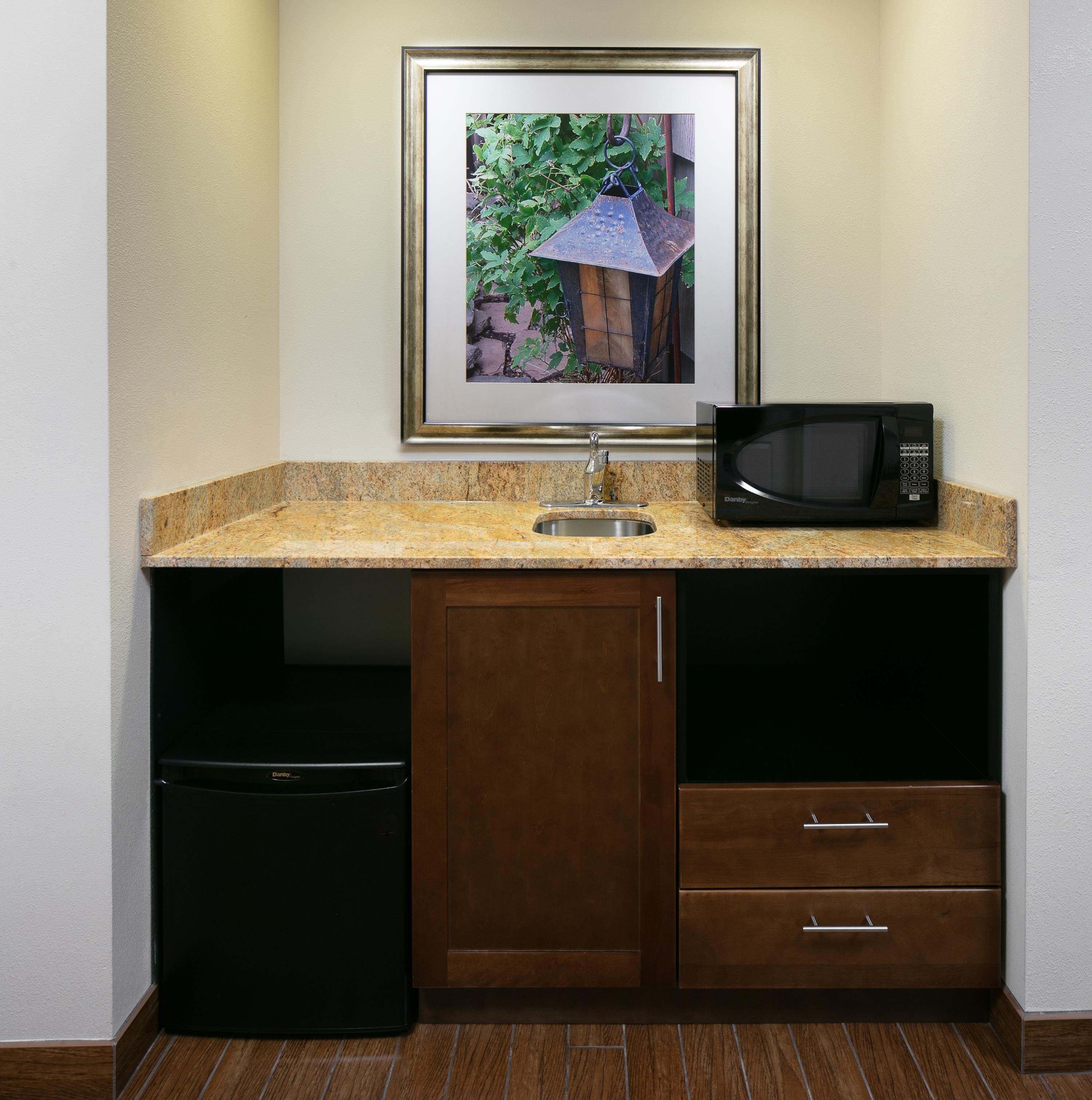 A kitchenette with a framed picture, a sink, a microwave, and a dishwasher.