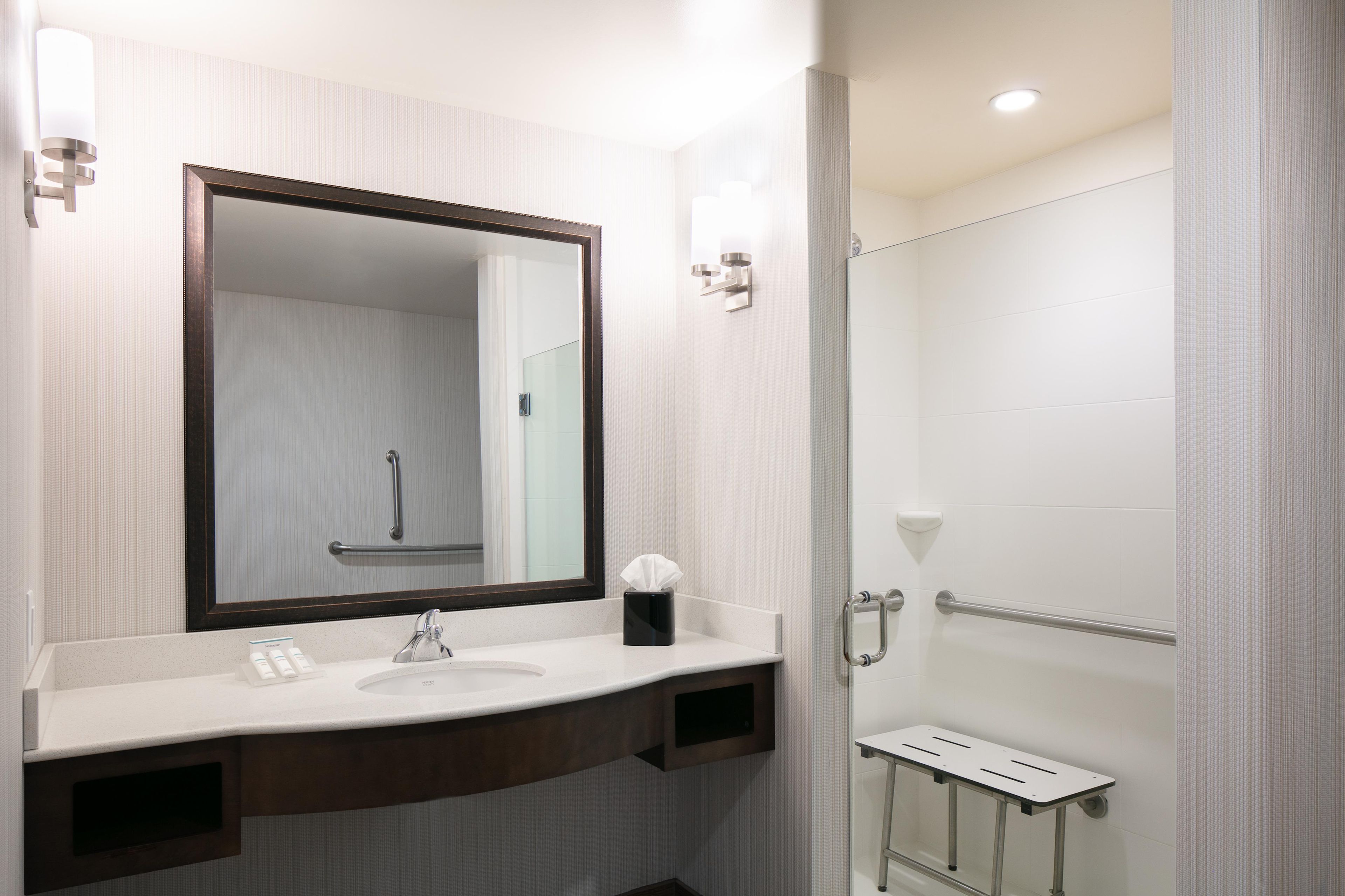A modern bathroom with a large mirror, a sink, and a shower area.