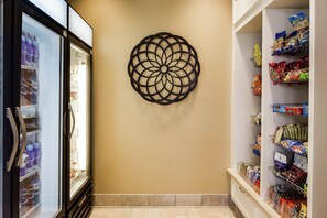 Un couloir agrémenté d’un élément décoratif mural, d’un présentoir réfrigéré pour les boissons et d’étagères remplies de collations.
