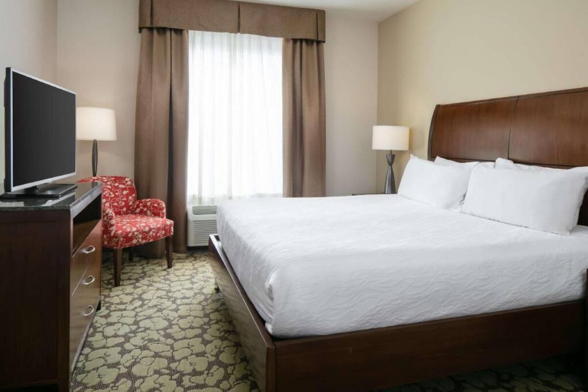 A hotel room with a bed, a television, a desk, and a chair.