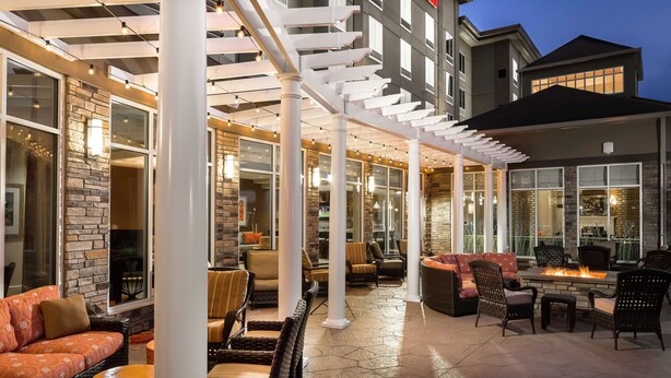 An outdoor patio area with seating arrangements, a fire feature, and a stone wall.