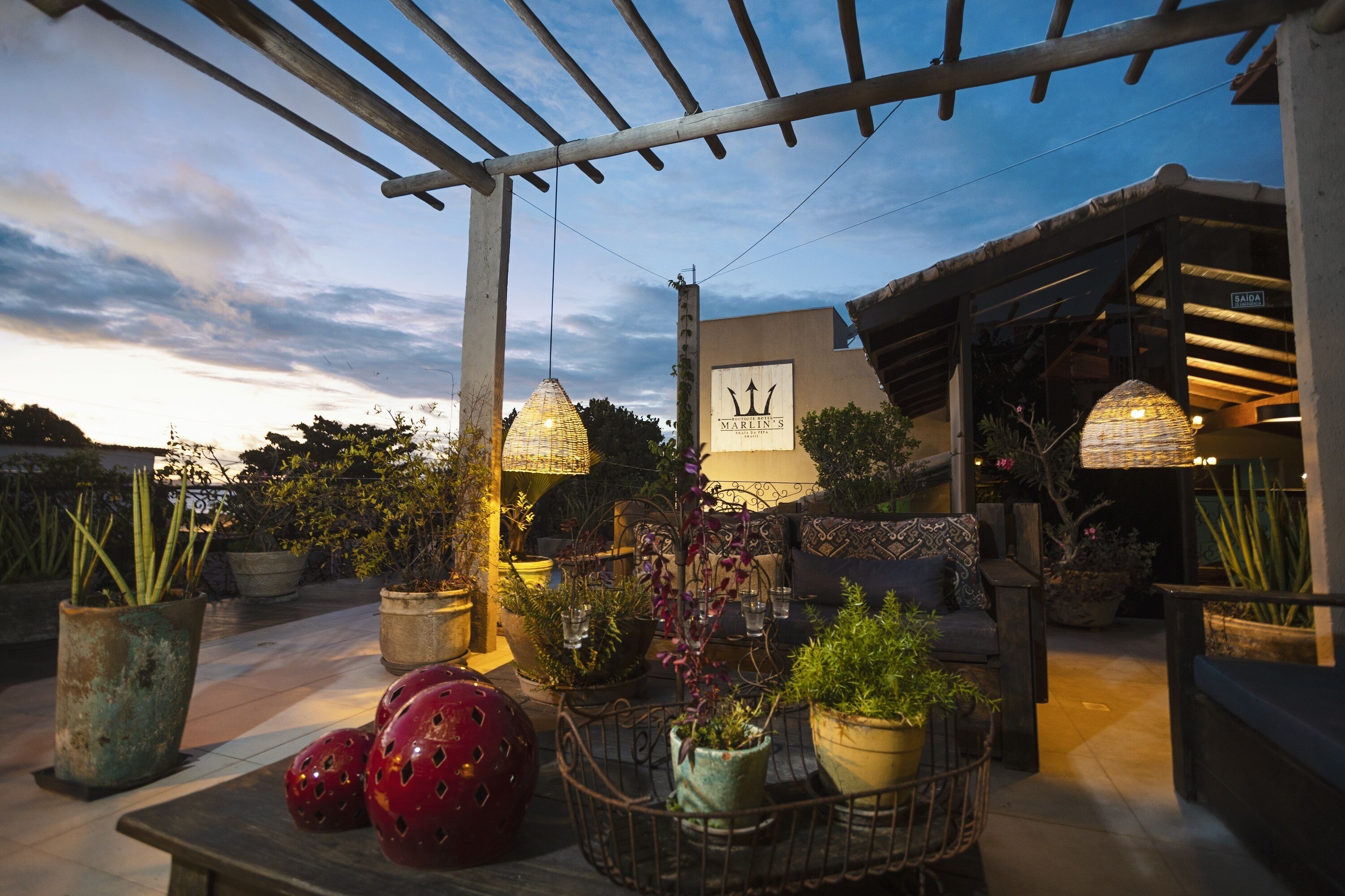 Een terras met potplanten, een houten pergola en een bordje met de naam Marlin's.