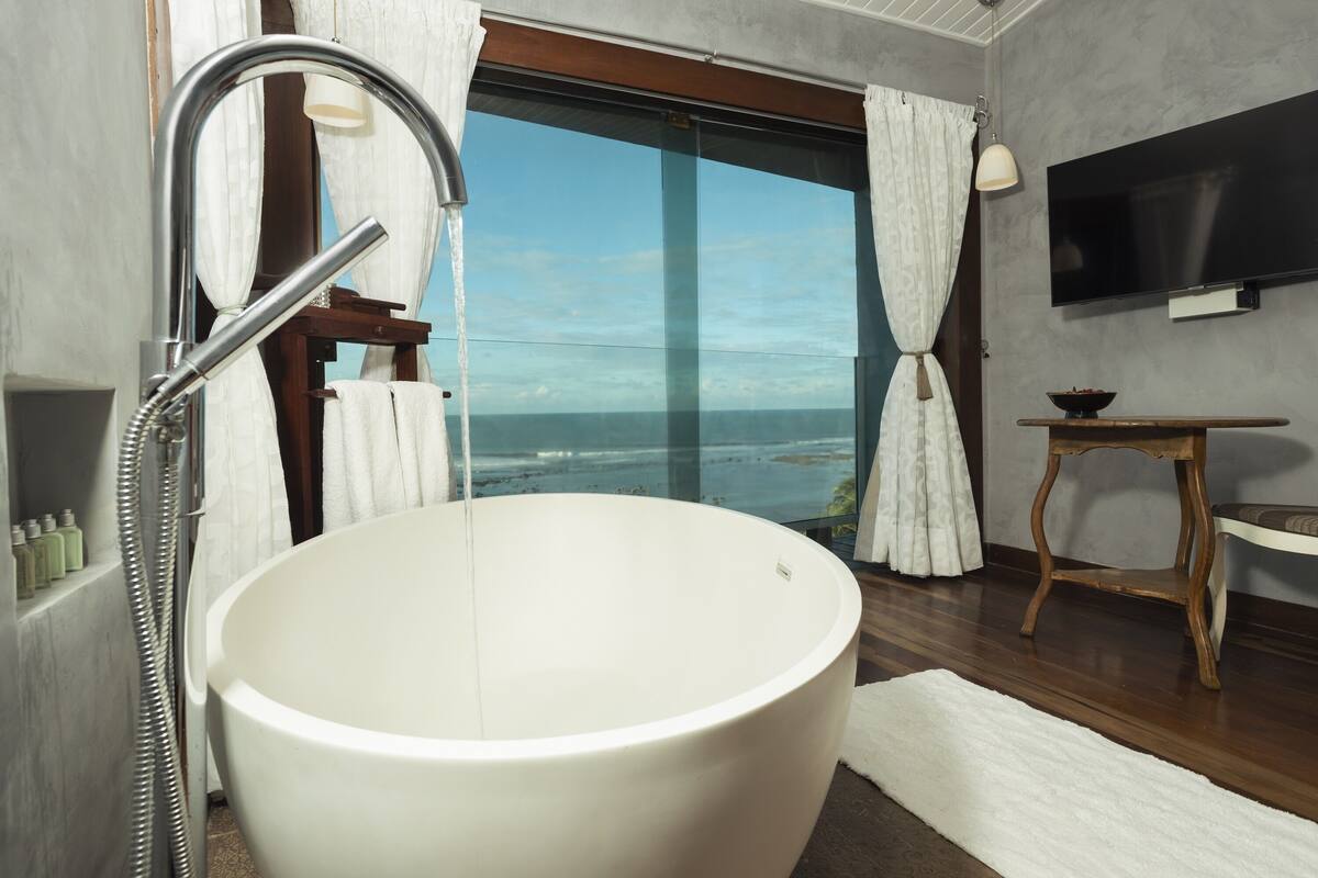 Une salle de bain moderne dotée d’une grande baignoire, d’une douche et offrant une vue sur l’océan.