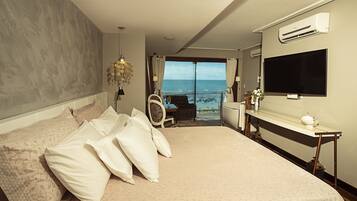 A spacious bedroom with a large bed, a TV, and a view of the ocean.