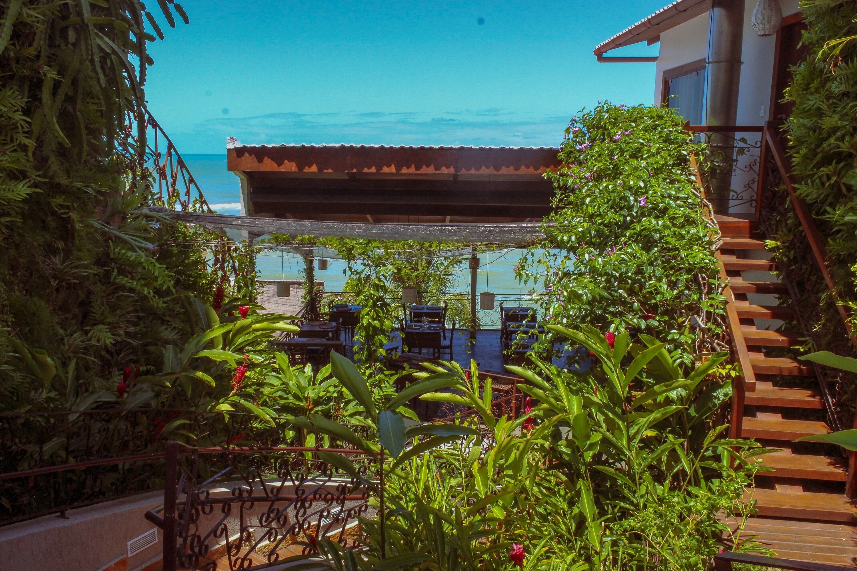 Una terraza con mesas al aire libre, una escalera y vista al océano.