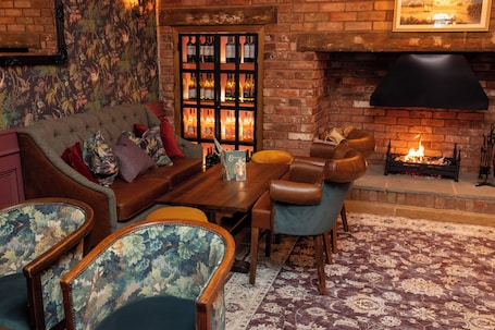 A cozy living room with a brick fireplace, a sofa, a coffee table, and patterned chairs.. Himley House Hotel by Chef and Brewer Collection