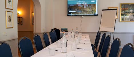 A conference room with a long table, chairs, a screen, and a projector.