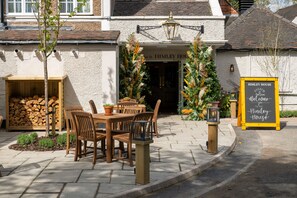 Une table et des chaises en bois sont placées à l’extérieur d’un bâtiment sur lequel on peut lire l’inscription « Himley House ».