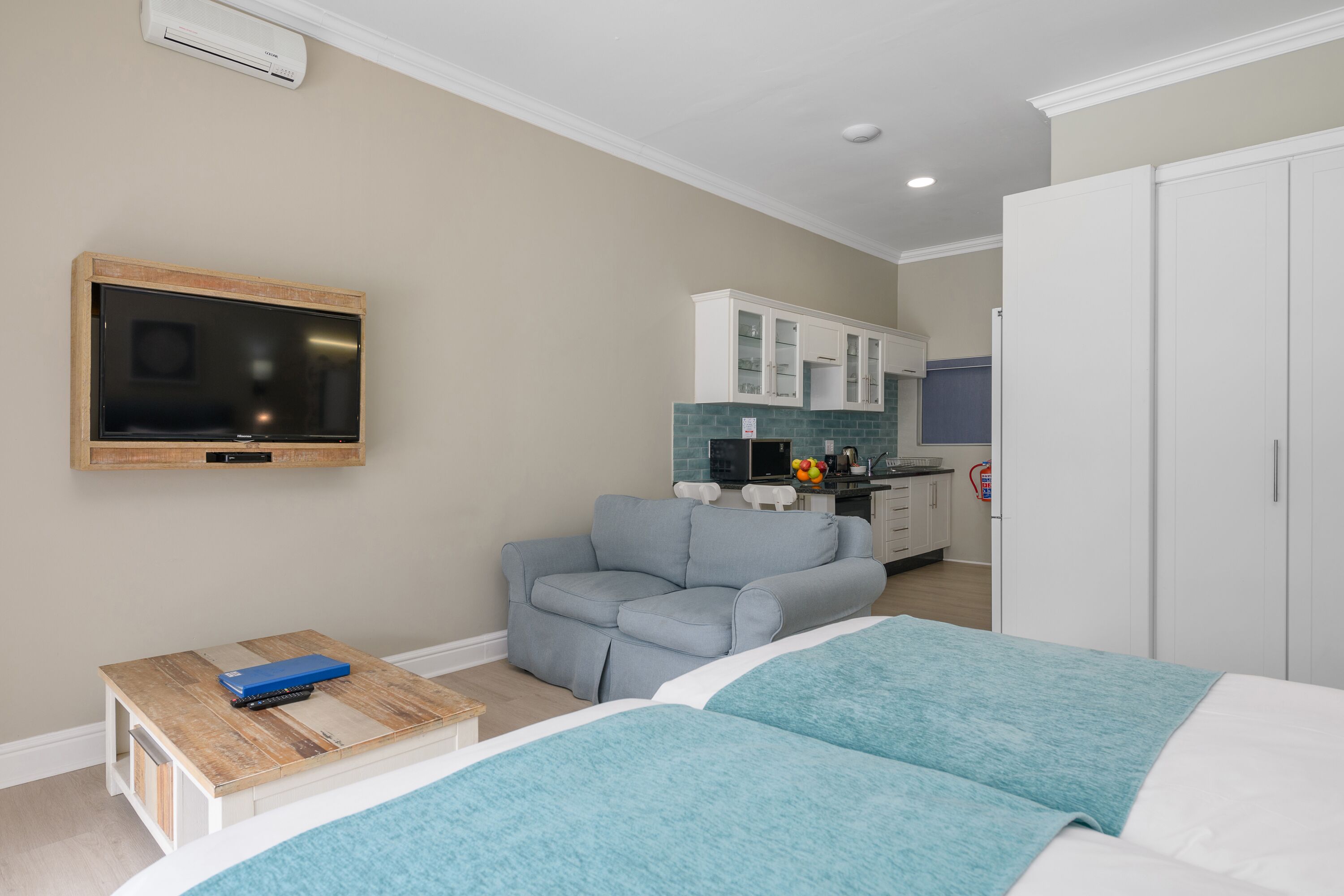 A bedroom with a bed, a TV, a sofa, and a small table.