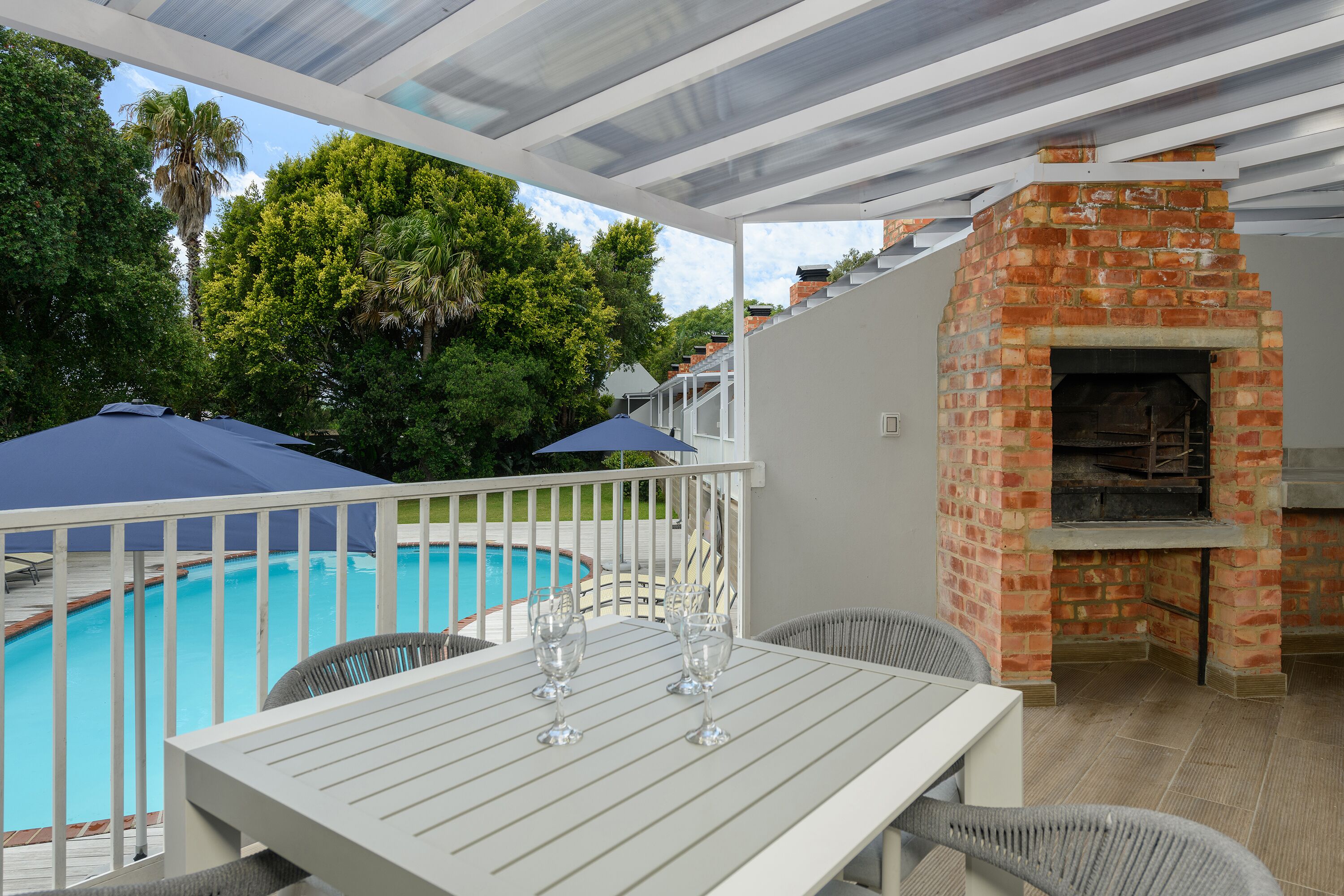 Un patio exterior con piscina, horno de ladrillo y zona de estar cubierta.