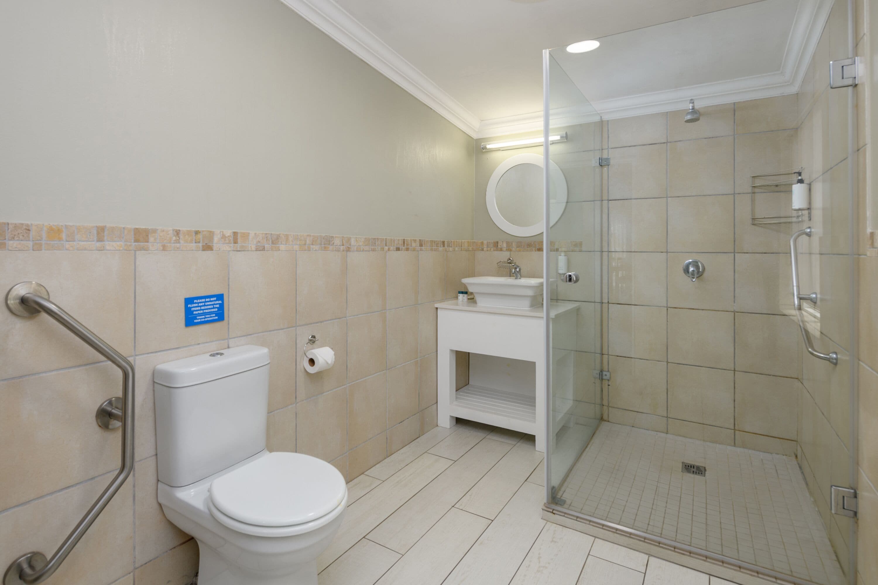 Un baño con inodoro, lavamanos y cabina de ducha con mampara de vidrio.