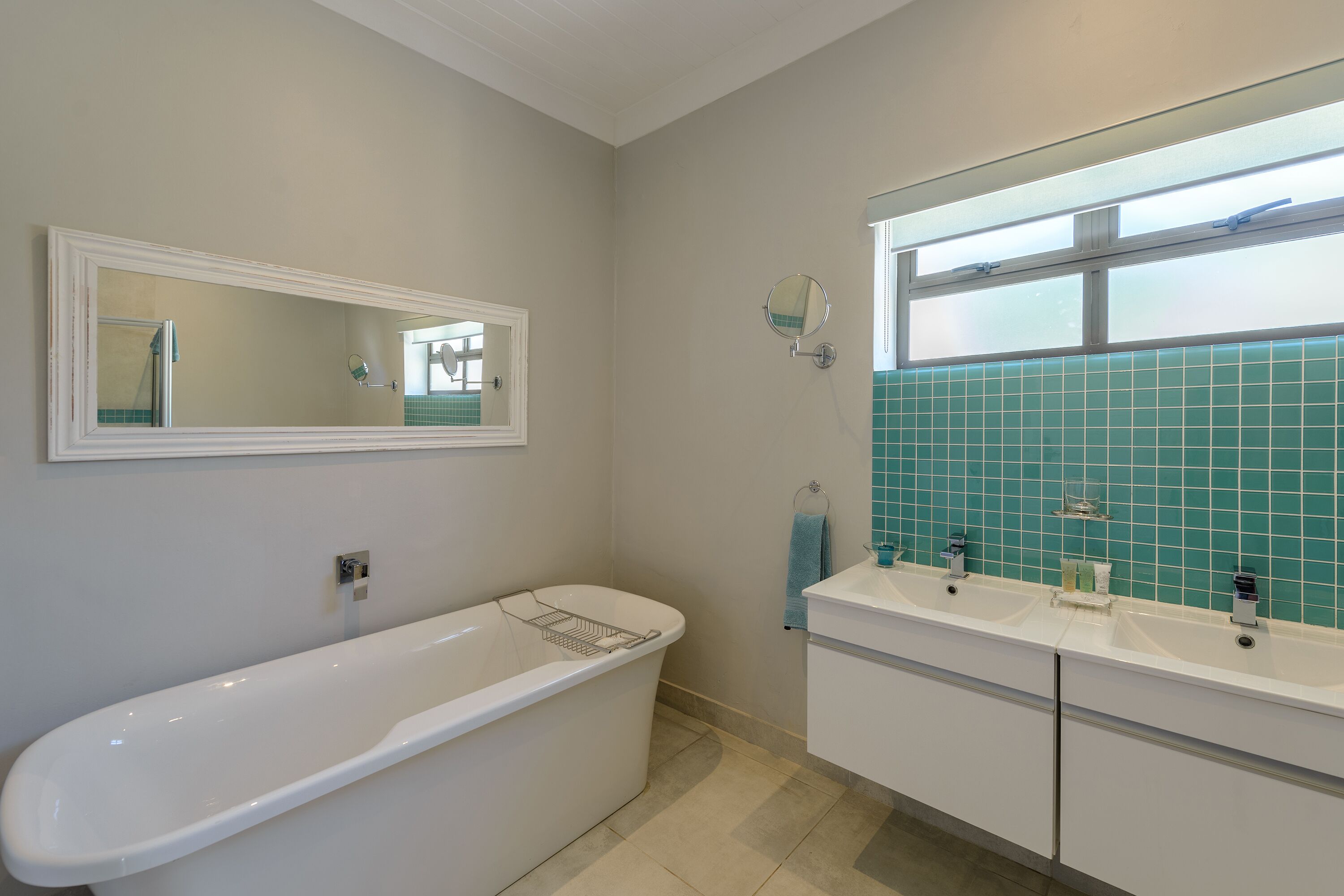 A bathroom with a freestanding bathtub, a double sink vanity, and a mirror above the sink.