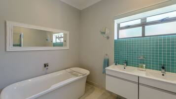 A bathroom with a freestanding bathtub, a double sink vanity, and a mirror above the sink.