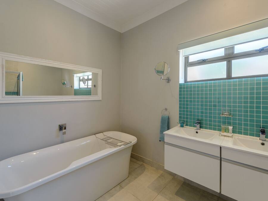 A bathroom with a freestanding bathtub, a double sink vanity, and a mirror above the sink.