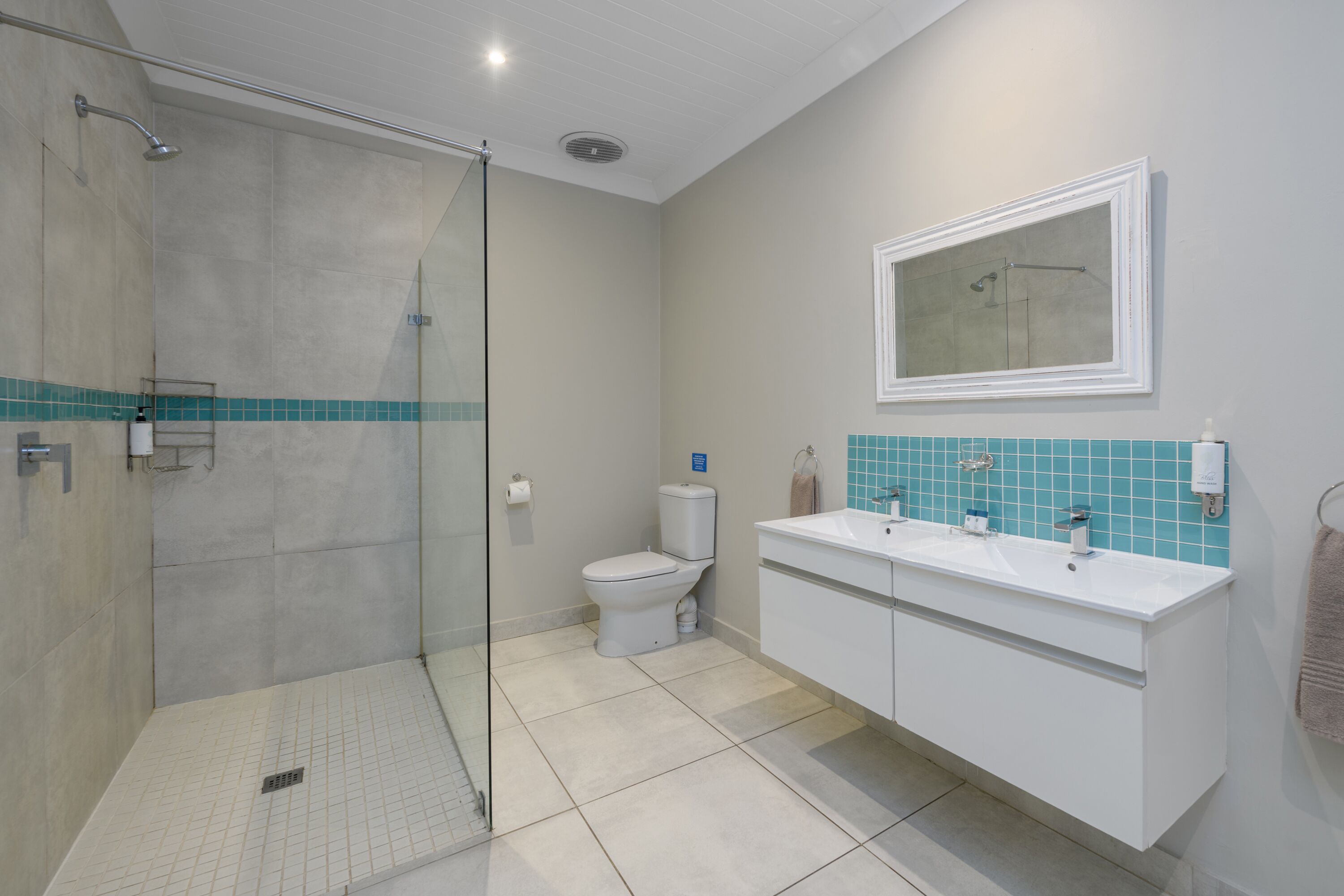 Une salle de bain avec une douche à parois de verre, des toilettes et un meuble-lavabo avec un miroir.