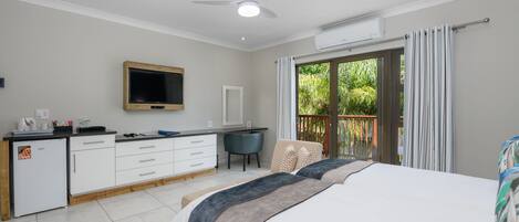 A hotel room with a bed, a desk, a chair, a TV, and a balcony with curtains.