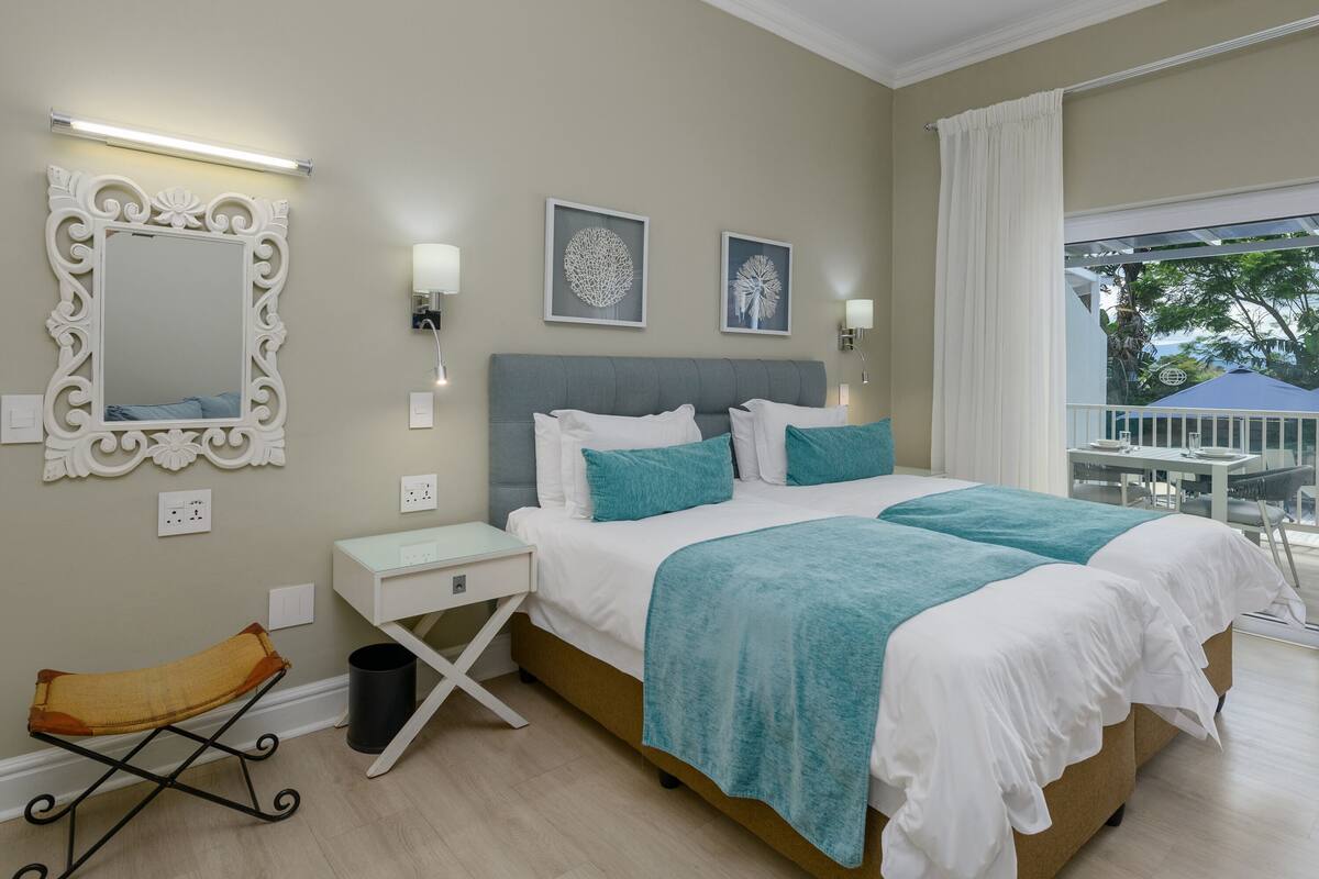 A bedroom with a large bed, a bedside table, a chair, and a window with a view of the outdoors.