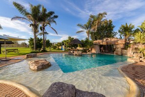 A clear swimming pool with rock formations and palm trees. - Formosa Bay (Plettenberg Bay)