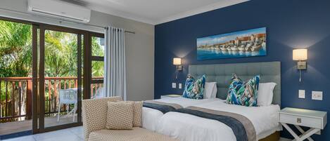 A bedroom with a bed, a sofa, a ceiling fan, and a painting on the wall.