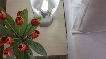 Un comodino con una lampada e un vaso con tulipani rossi.