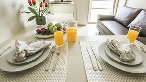 A breakfast setting with plates, cutlery, fruits, and glasses of orange juice on a table. - Verona Hplus Long Stay (Lago Norte)