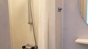 A shower with a handheld showerhead and a wall-mounted faucet.