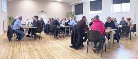 A conference room with wooden floors, multiple tables, and chairs arranged for a meeting.