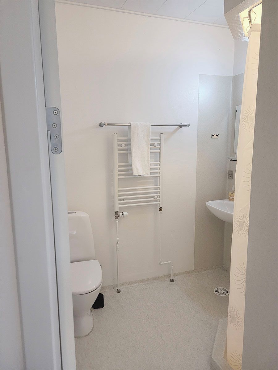 Un baño pequeño y limpio con inodoro, toallero y lavabo.