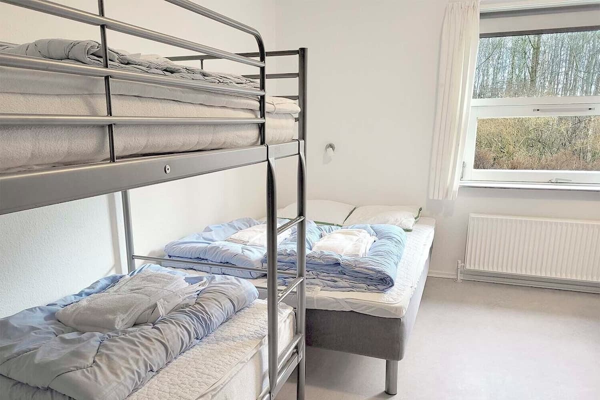 Dormitorio con literas, ventana y radiador.