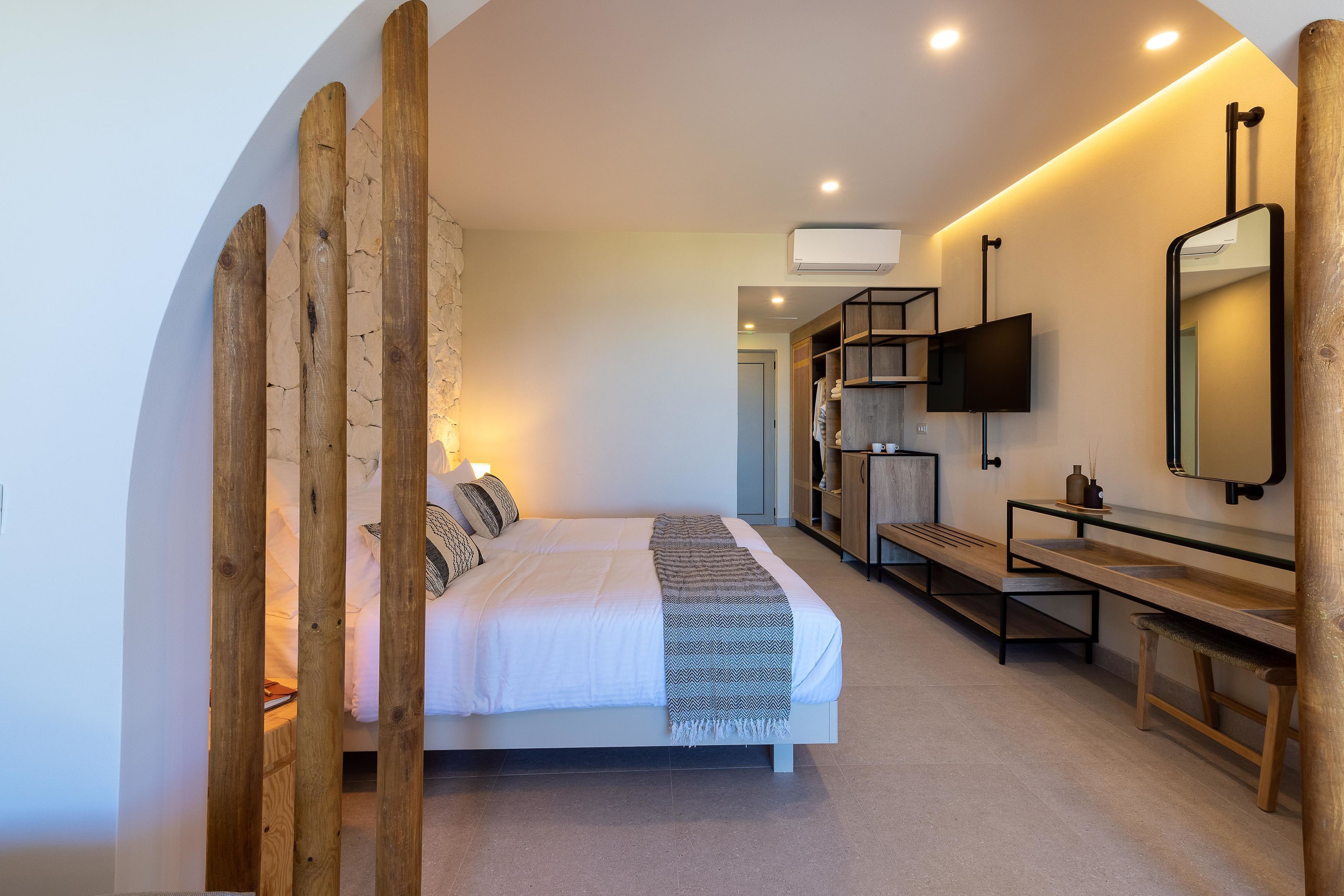A modern bedroom with a bed, bedside tables, a TV, and a mirror.