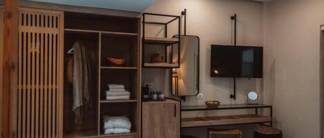 A modern bedroom with a built-in wardrobe, a bedside table, a TV, and a small stool.
