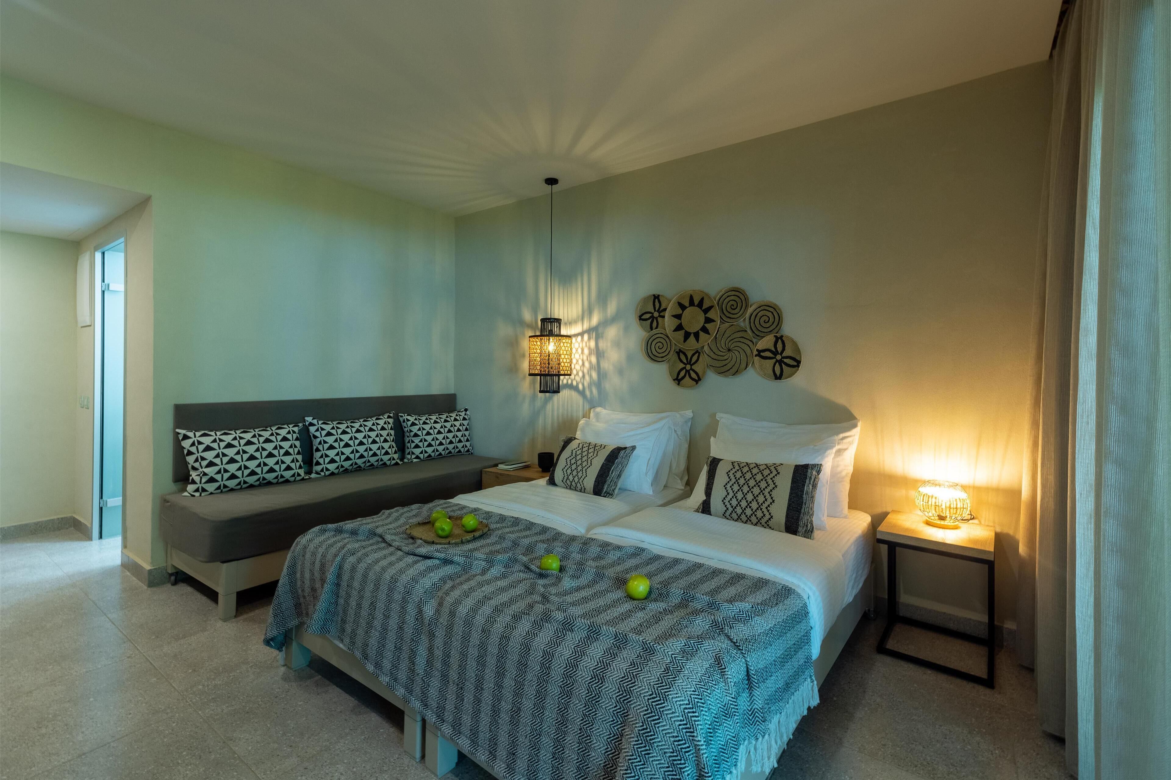 A bedroom with a bed, bedside tables, a bench, and wall decor.