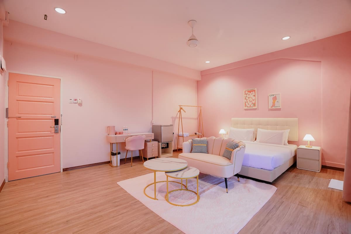 A pink-themed bedroom with a bed, bedside tables, a desk, and a swing chair.