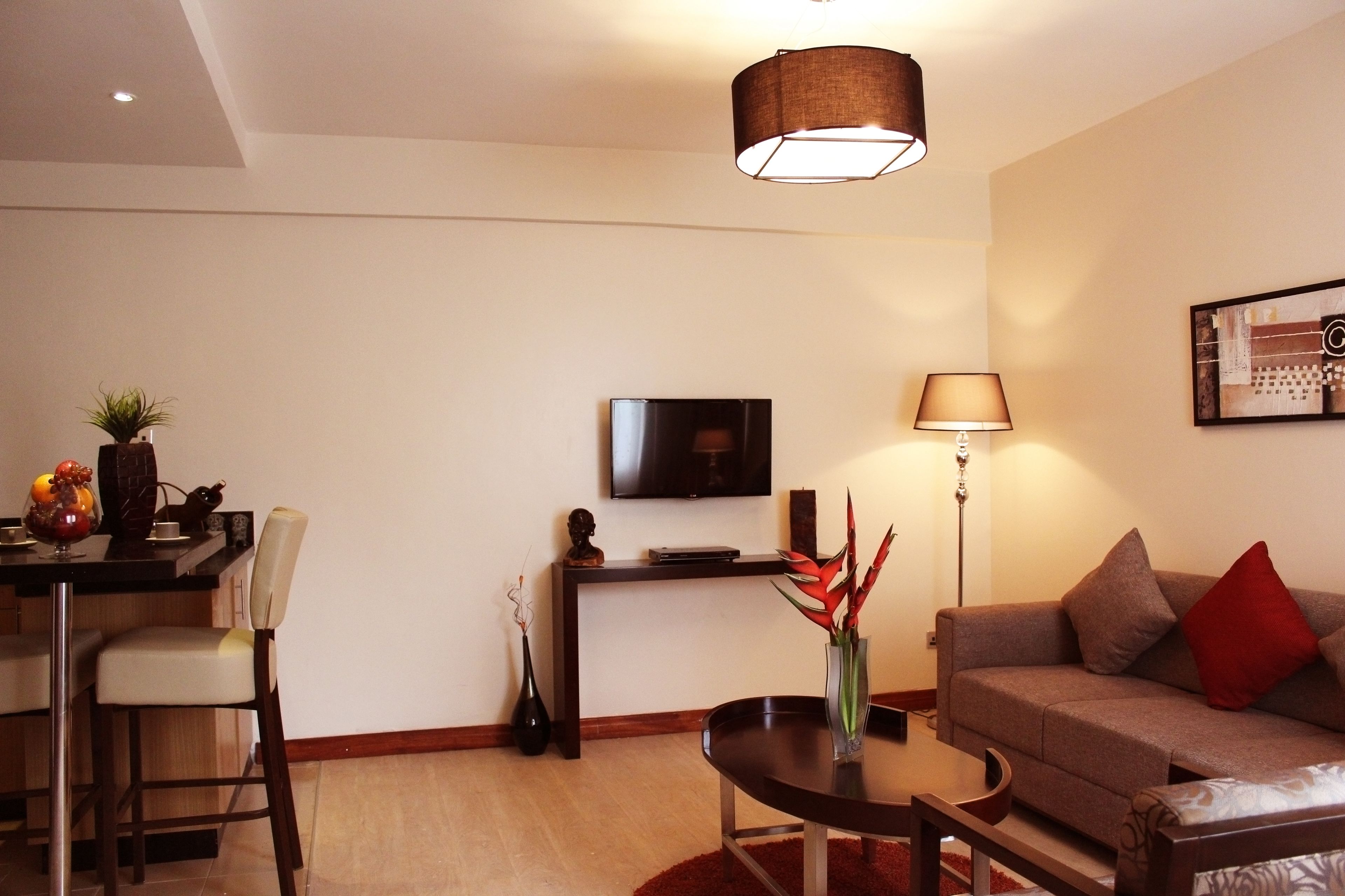 A modern living room with a sofa, a coffee table, a TV, and a dining area with chairs and a small table.