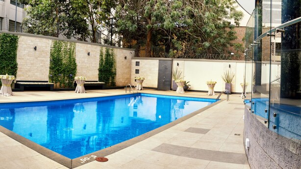 A swimming pool with a tiled deck, surrounded by a patio area with outdoor seating.