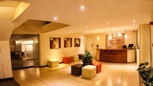 A hotel reception area with a reception desk, several seating options, and artwork on the walls.