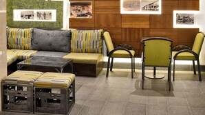 A modern interior with a wooden ceiling, green accent wall, and a seating area with a sofa and chairs.