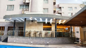 A modern hotel with a pool, outdoor seating, and a bar area.