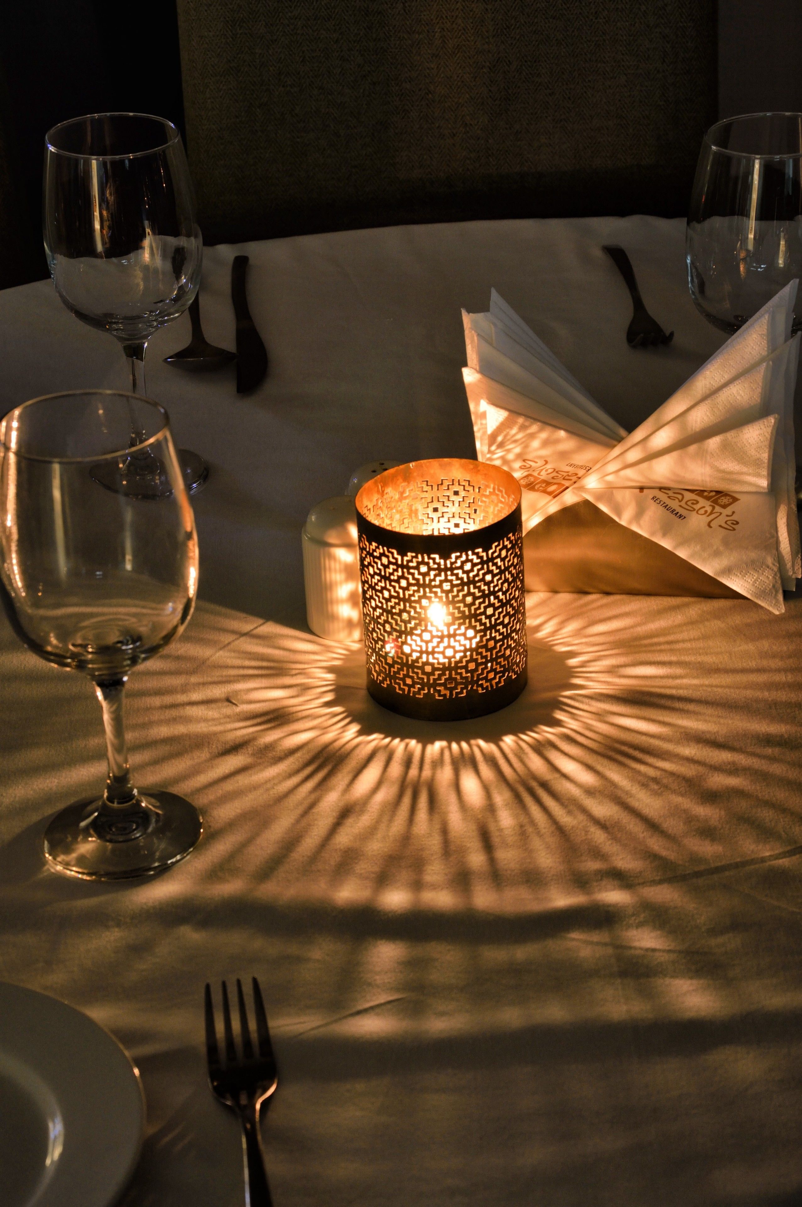 A table set for dining with a candle and wine glasses.