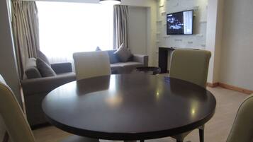 A modern living room with a round table, two sofas, and a flat-screen TV mounted on the wall.