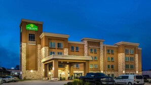 Un hôtel La Quinta Inn & Suites doté d’une façade en pierre, de nombreuses fenêtres et d’une entrée abritée.