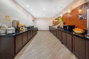 Une cuisine moderne dotée d’un long comptoir, d’appareils électroménagers intégrés et d’un mur d’accent en bois.