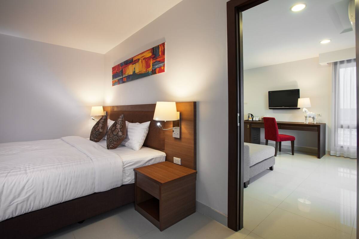 Une chambre d’hôtel comprenant un lit, une table de chevet, une lampe et un bureau avec une chaise.