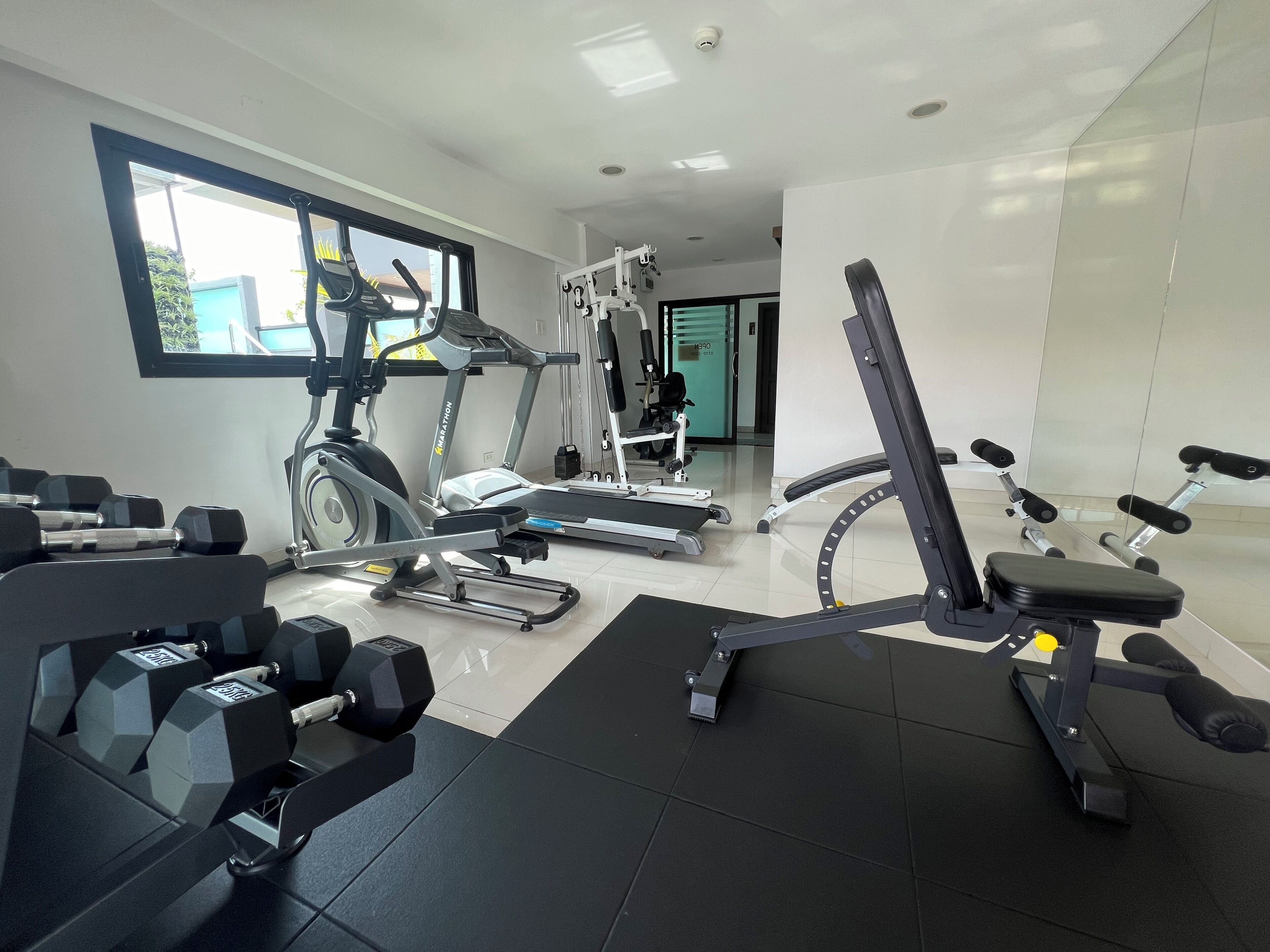 A gym with cardio machines, weightlifting equipment, and a mirrored wall.