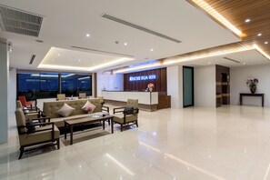 A modern hotel lobby with a reception desk, seating area, and a large window offering a view of the outside. - Riche Hua Hin (Hua Hin)
