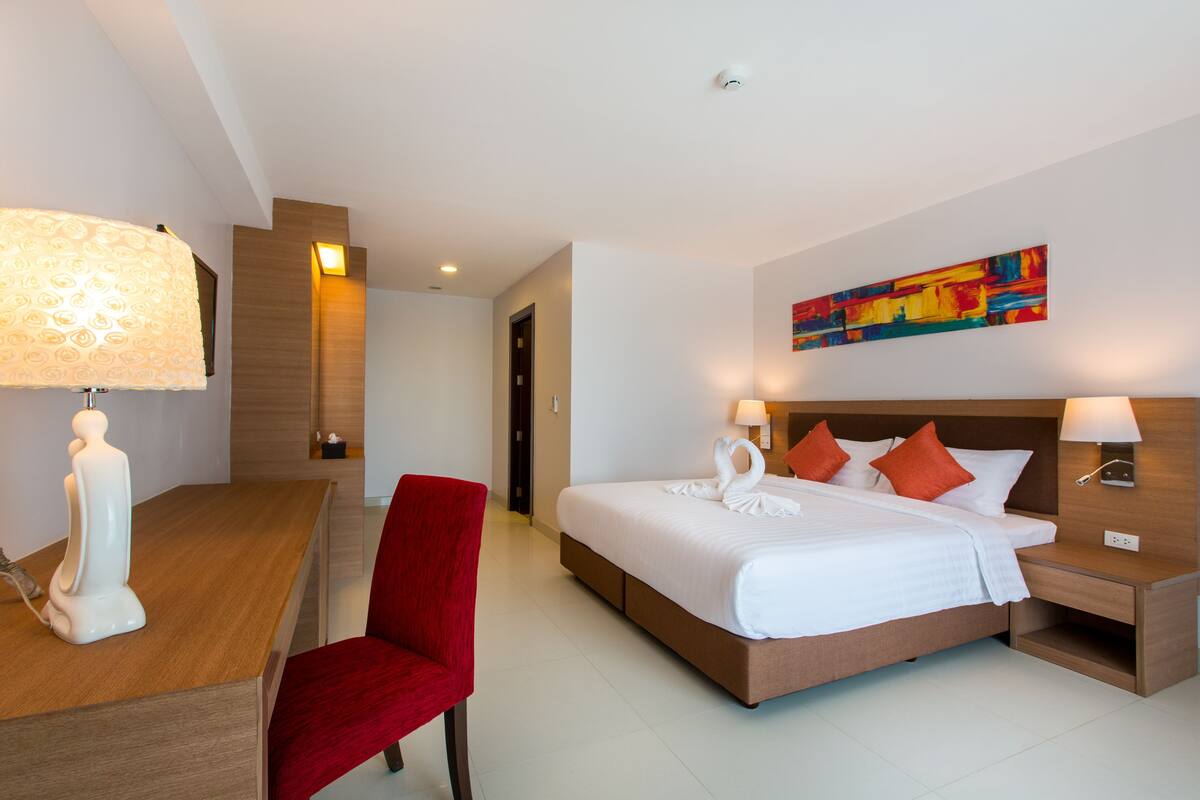 Une chambre d’hôtel avec un lit, un bureau, une chaise et une table de chevet.