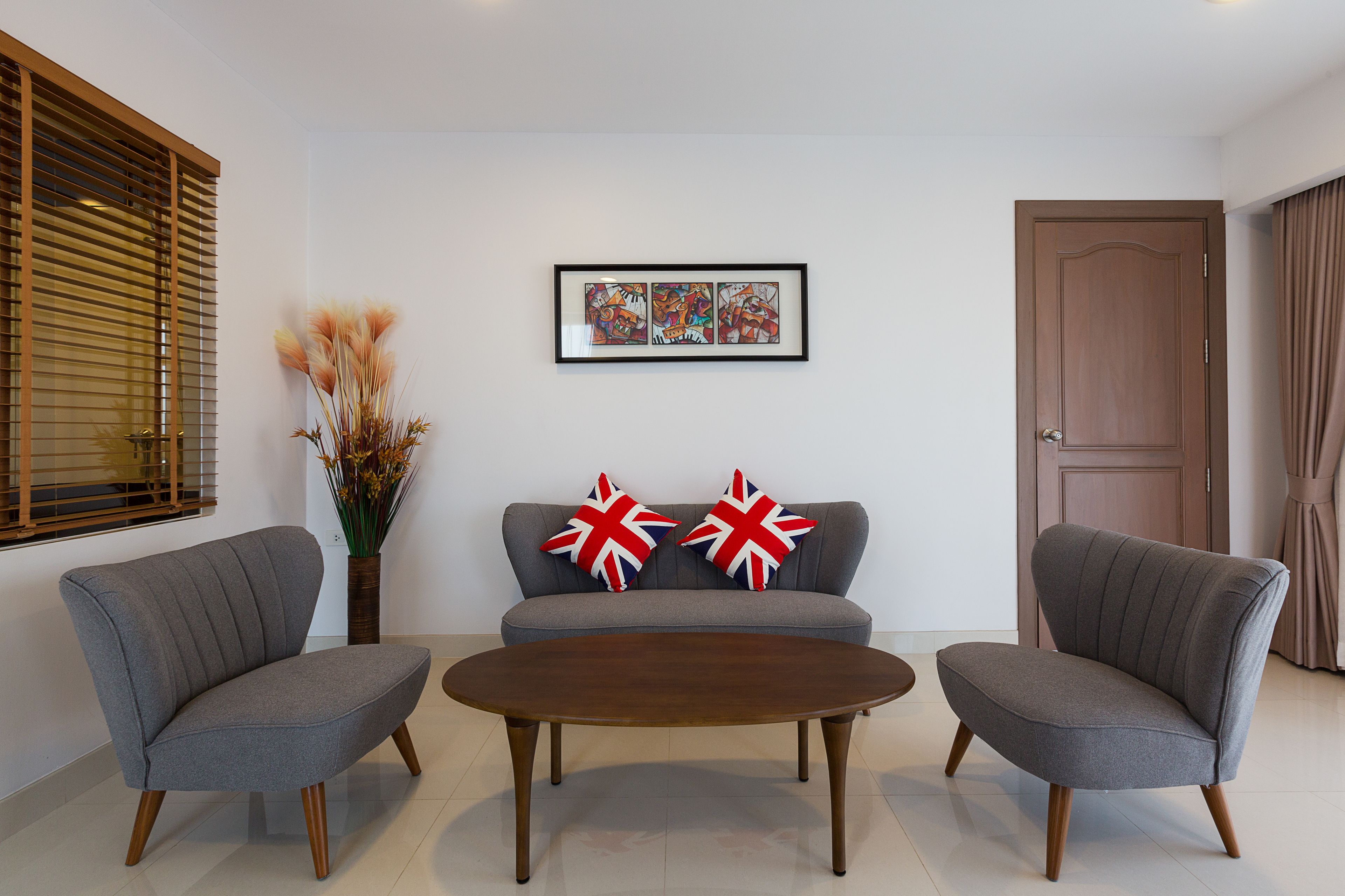 A modern living room with a grey sofa, two armchairs, a wooden coffee table, and a framed artwork on the wall.