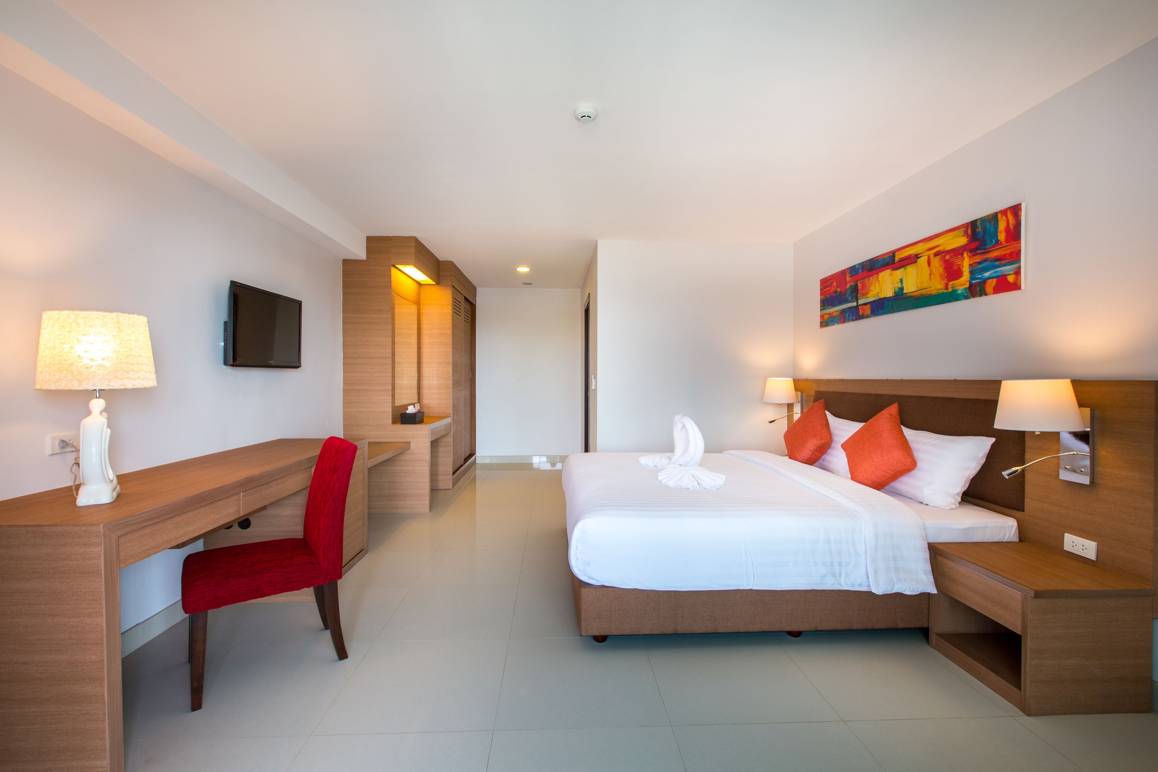 A hotel room with a bed, a desk, a chair, and a TV.