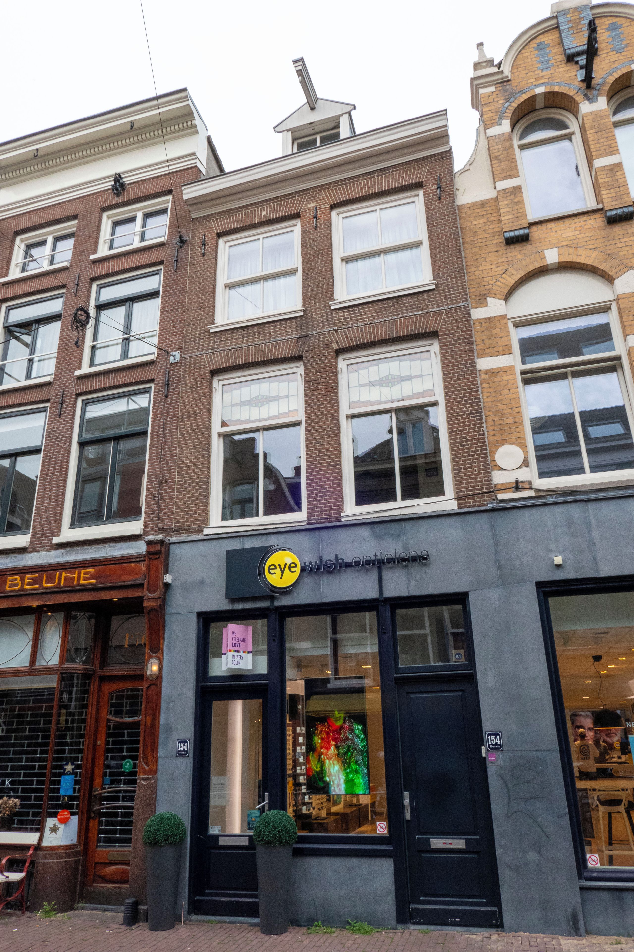 Un edificio de varios pisos con escaparate que muestra un letrero de 'eye wish opticians'.