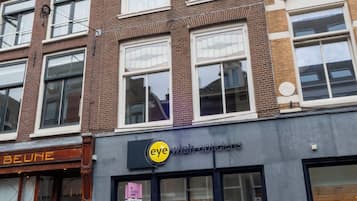 Ein mehrstöckiges Gebäude mit einer Schaufensterfront, auf der ein Schild für 'eye wish opticians' zu sehen ist.